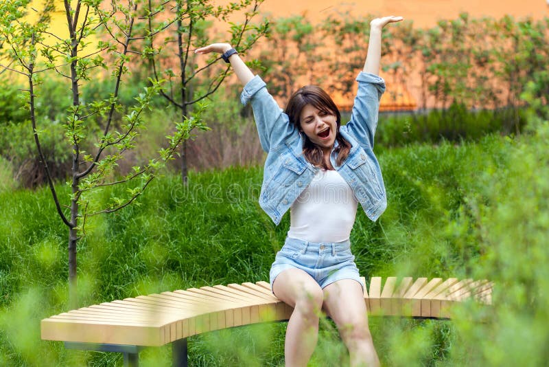 美丽的年轻深色的妇女画象在蓝色偶然牛仔布样式开会和室外春天,打呵欠与闭合的眼睛和 库存图片 美丽的年轻深色的妇女画象在蓝色偶然牛仔布样式开会和室外春天,打呵欠与闭合的眼睛和 库存图片